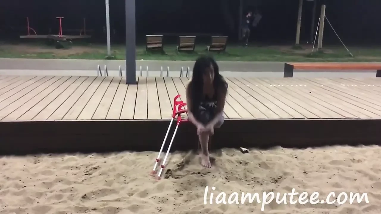 Amputee woman with crutches on the beach
