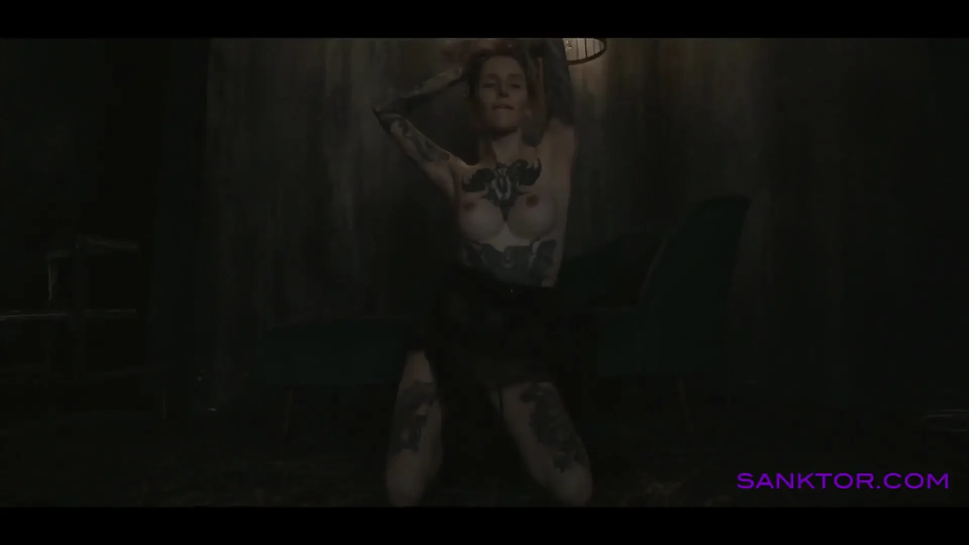 Tattooed teen is dancing in the dark room